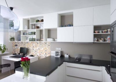 Interiér panelákového bytu, Marimekko, tapeta, kuchyň, kuchyňská linka, jídelní stůl, skříňky nad stolem, pracovní stůl, závěsné světlo, bílá kuchyň, tmavá deska