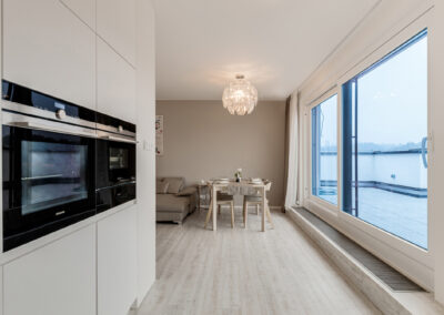 Luxusní byt v novostavbě, kuchyň, scandi styl, skandinávský styl, bílý lesk, skříň, kuchyň na míru, jídelní stůl, design světlo