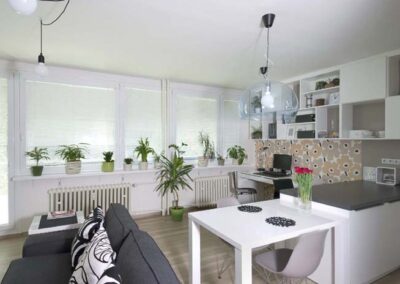 Interiér panelákového bytu, Marimekko, tapeta, kuchyň, kuchyňská linka, jídelní stůl, police, pracovní stůl, závěsné světlo, pokojové rostliny