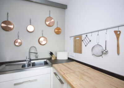 Interiér bytu Řešovská, panelákový byt, kompletní rekonstrukce, měděné pánve na zdi, kuchyň, nerezový dřez, vybavení kuchyně