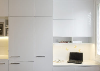 Interiér panelákového bytu, kuchyň, kuchyňská linka, bílá kuchyň, dřevěná podlaha, skříňky, pracovní kout, pracovní místo