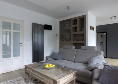 Proměna obývacího pokoje, RD Nučice, pohovka, křeslo, starožitní konferenční stolek, vestavěné bodové osvětlení, vertikální antracitový radiátor, vestavěné police v nice, koberec na dlažbě