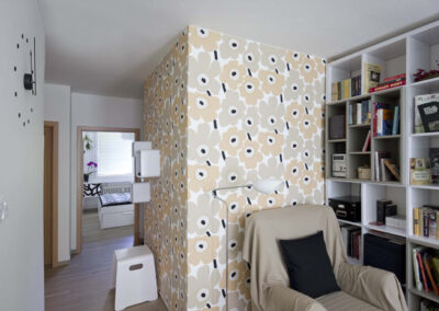 Interiér panelákového bytu, Marimekko tapeta, křeslo, knihovna, pohled do chodby