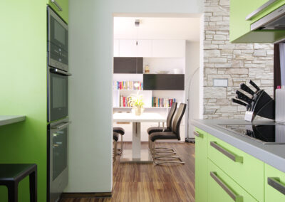 Panelákový byt, Zlín, jídelní stůl, knihovna, bar, černé židle, zelená kuchyň