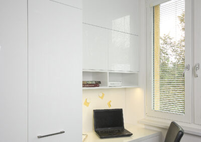 Interiér panelákového bytu, kuchyň, kuchyňská linka, bílá kuchyň, dřevěná podlaha, skříňky, pracovní kout, pracovní místo