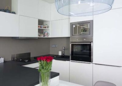 Interiér panelákového bytu, Marimekko, tapeta, kuchyň, kuchyňská linka, jídelní stůl, kuchyň do U, tmavá deska, bílá kuchyň, závěsné světlo