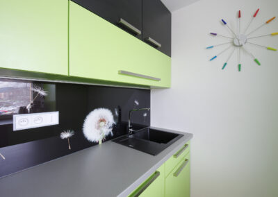 Panelákový byt, Zlín, zelená kuchyň, nástěnné hodiny, černé sklo