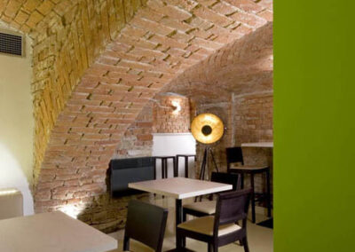 Interiér baru v Poděbradech, cihlové klenby, světlá litá podlaha, tmavé dřevo, jídelní židle, jídelní stoly, zelený sloup