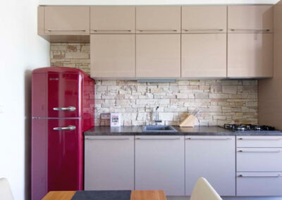 Interiér cihlového bytu, obytný prostor s kuchyní, lanýžová kuchyně, červená retro lednice, kamenný obklad v kuchyni, jídelní stůl, jídelní židle, vinylová podlaha