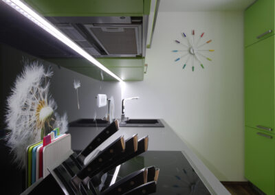 Panelákový byt, Zlín, zelená kuchyň, nástěnné hodiny, černé sklo