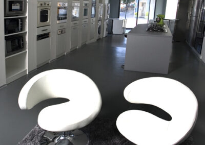 Největší showroom, zn. Whirlpool, prodejna, komerční prostor, komerční interiér, prodejní pult, vestavěné spotřebiče, šedá podlaha, litá podlaha, bílá křesla