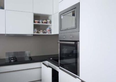 Interiér panelákového bytu, Marimekko, tapeta, kuchyň, kuchyňská linka, jídelní stůl, kuchyň do U, tmavá deska, bílá kuchyň