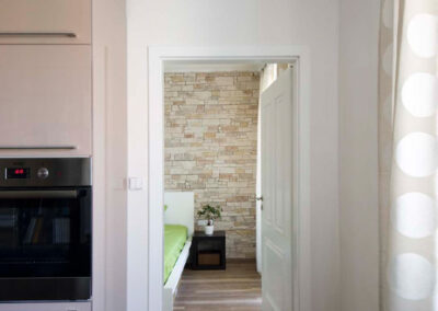 Interiér cihlového bytu, obytný prostor s kuchyní, lanýžová kuchyně, pohled do ložnice, kamenný obklad, vinylová podlaha