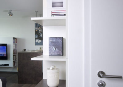 Interiér bytu Řešovská, panelákový byt, kompletní rekonstrukce, knihovna, otevřená knihovna, police, pohled z chodby do obývacího pokoje, tmavá vinylová podlaha, TV nábytek