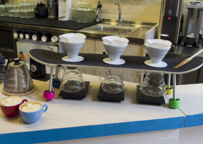 Interiér kavárny AnonymouS, postup přípravy kávy, skateboard jako podnos, hrnky s filtrem, recyklovaný skateboard