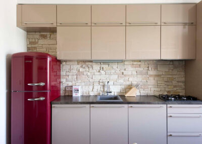 Interiér cihlového bytu, obytný prostor s kuchyní, lanýžová kuchyně, červená retro lednice, kamenný obklad v kuchyni