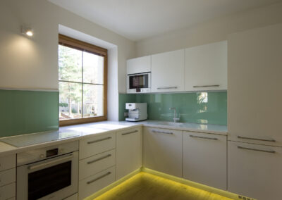 Řadový dům, kuchyň, kuchyňská linka, zelené sklo, bílá kuchyň, okno v kuchyni, dřevěná podlaha