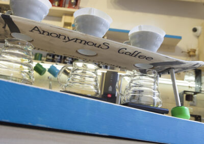 Interiér kavárny AnonymouS, postup přípravy kávy, skateboard jako podnos, hrnky s filtrem, recyklovaný skateboard