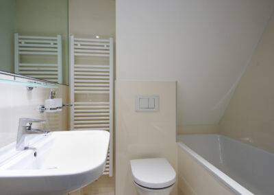 Luxusní byt, koupelna, béžové obklady, umyvadlo, zrcadlo, vana, radiátor