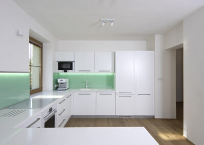 Řadový dům, kuchyň, kuchyňská linka, zelené sklo, bílá kuchyň, okno v kuchyni, dřevěná podlaha