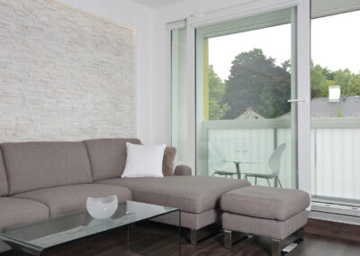 Panelákový byt, obytný prostor, obývák, vinylová podlaha, TV nábytek, konferenční stůl, velké balkonové okno, pohovka, taburet, lodžie, sezení na balkoně, kamenný obklad