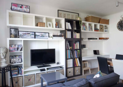 Interiér cihlového bytu, obytný prostor s kuchyní, tmavě šedá pohovka, vinylová podlaha, knihovna, pracovní kout, TV, televize