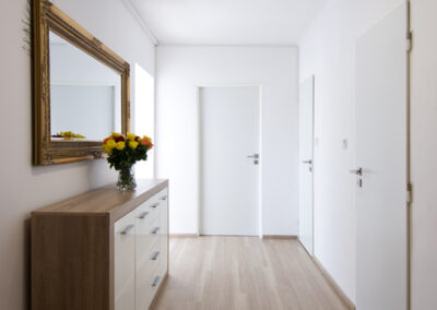 Panelákový byt, chodba, komoda, zrcadlo, dekorativní rám, zrcadlo ve zlatém rámu, vinylová podlaha