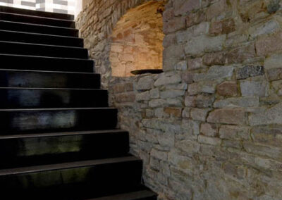 Interiér baru v Poděbradech, cihlová zeď, nika v cihlové zdi, nepřímé osvětlení, černé schodiště