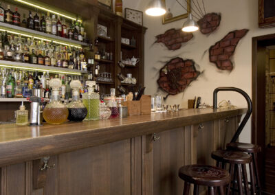 Interiér baru AnonymouS, tmavé dřevo, obraz na zdi, logo na zdi, bar, vyryté logo na barové židli