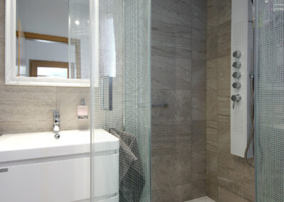 Rekonstrukce, rodinný dům, přízemí, koupelna, sprchový kout, umyvadlo se skříňkou, zrcadlo, osvětlení v koupelně, sprchový panel, záchod, WC, šedý obklad