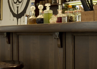 Interiér baru AnonymouS, tmavé dřevo, obraz na zdi, logo na zdi, bar, vyryté logo na barové židli