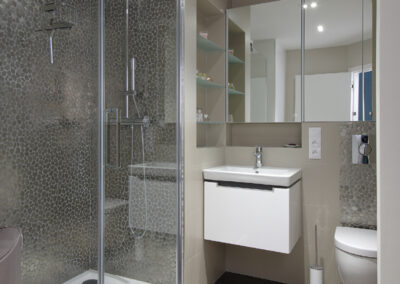 Panelákový byt, koupelna, radiátor, umyvadlo, zrcadlo, sprchový kout, sprcha, nerezová mozaika, béžový obklad, vinylové dílce, vinylová podlaha