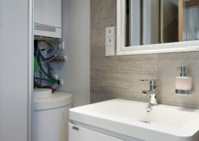 Rekonstrukce, rodinný dům, přízemí, koupelna, sprchový kout, umyvadlo se skříňkou, zrcadlo, osvětlení v koupelně, posuvné dveře, kotel, pračka