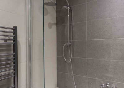 Interiér cihlového bytu, koupelna, radiátor, vana, sprchová zástěna, sprchový sloup