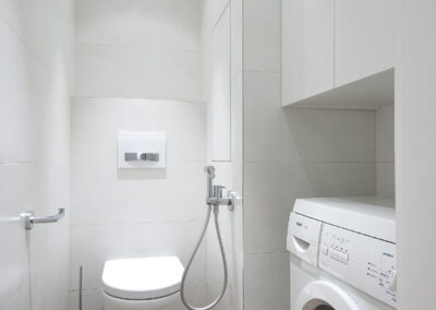 Interiér panelákového bytu, WC, záchod, pračka v nice, bidetová sprška, úložné skříně na záchodě