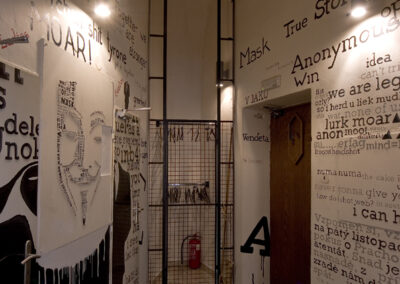 Interiér baru AnonymouS, tmavé dřevo, logo na zdi, nápisy na zdi, vstupní hala, vstup na WC, pomalované dveře, šatna