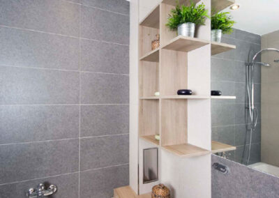 Interiér cihlového bytu, koupelna, nábytek v koupelně, velké zrcadlo, vana, umyvadlo, nábytek pod umyvadlem, police v koupelně