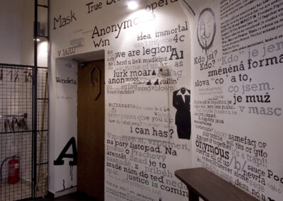 Interiér baru AnonymouS, tmavé dřevo, logo na zdi, nápisy na zdi, vstupní hala, pomalované dveře, šatna