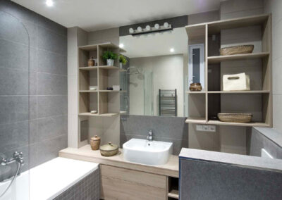 Interiér cihlového bytu, koupelna, nábytek v koupelně, velké zrcadlo, vana, umyvadlo, nábytek pod umyvadlem, police v koupelně