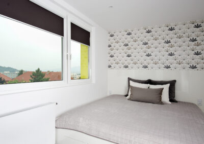 Panelákový byt, ložnice, postel, polštáře, noční stolek, tapeta, zastínění