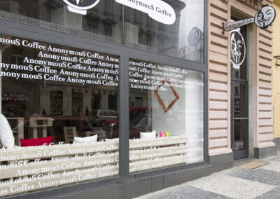 Interiér kavárny AnonymouS, vstup z ulice, vstup do kavárny, výloha s polepy, výloha s logem AnonymouS